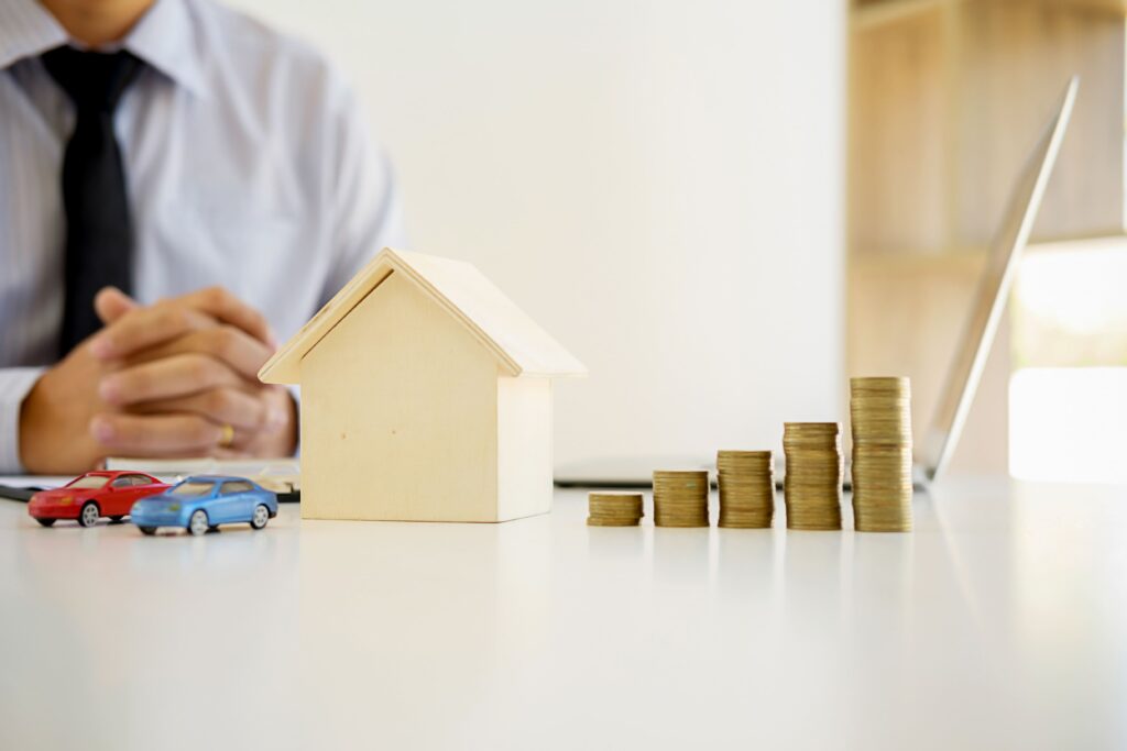 midsection-businessman-with-model-home-coins-table